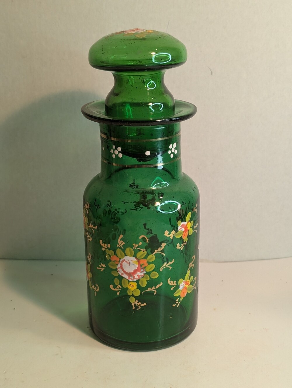 Vintage green glass decanter features charming hand-painted floral enamel detail